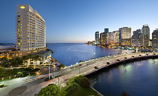 high rise buildings near body of water with bridge during golden hour